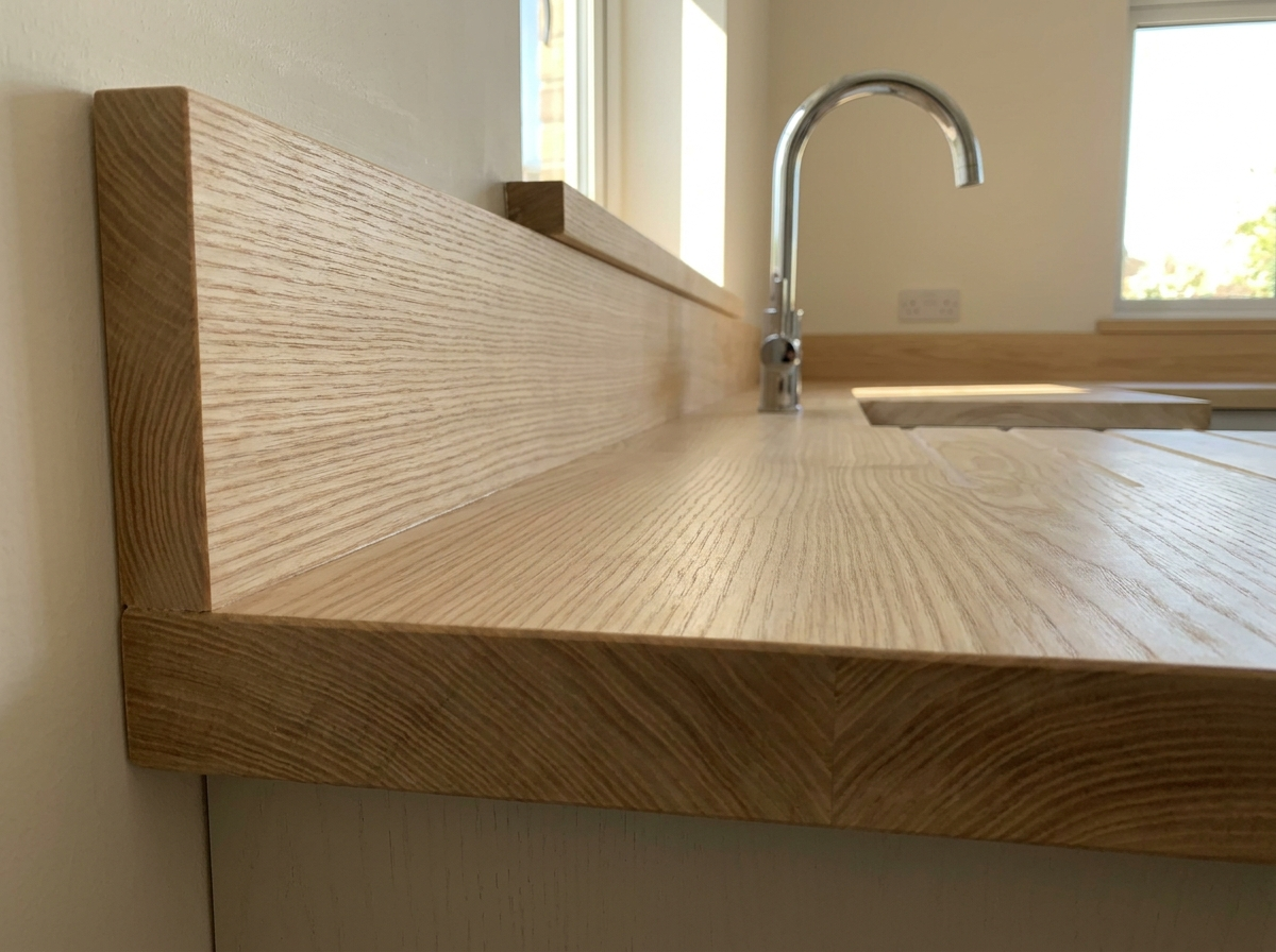 Solid ash worktop and matching upstand behind a chrome tap