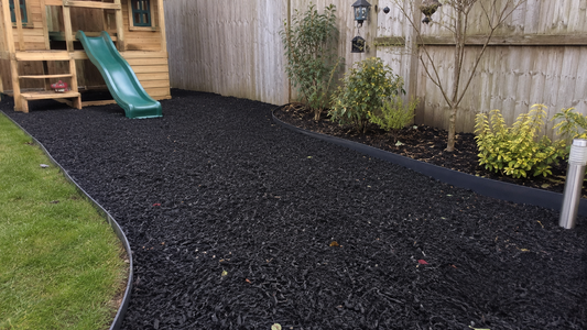 Playground rubber chippings surfacing a small play area and border in a UK domestic garden