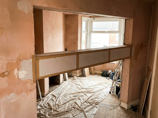 Steel RSJ beam boxed in with plasterboard over a knocked-through opening in a UK home — clean square casing ready for skim