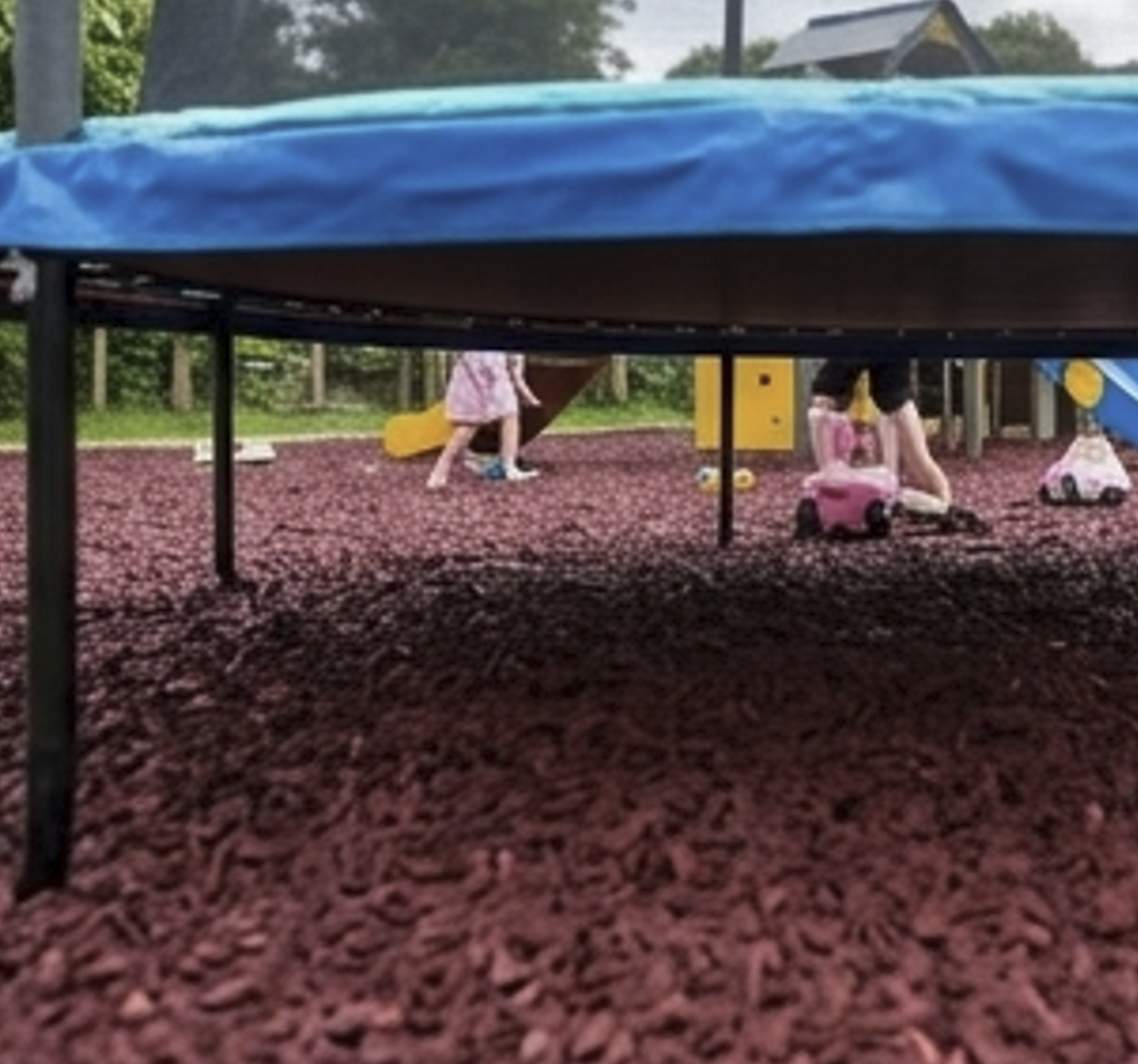 Rustic red rubber chippings under trampoline play area