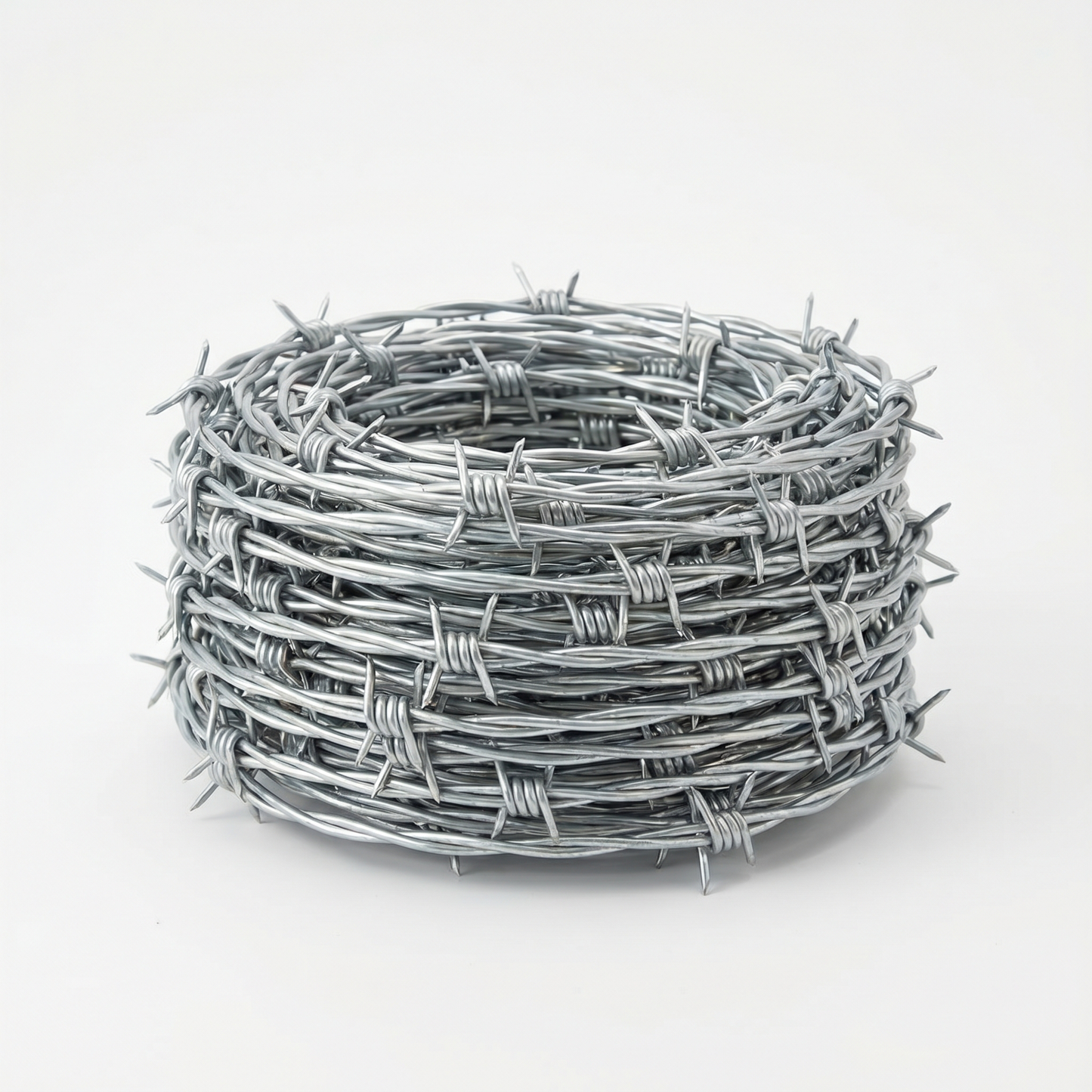 Coil of galvanised barbed wire on a white studio background
