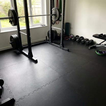 Smooth black rubber gym flooring with barbell and squat rack in a UK home gym