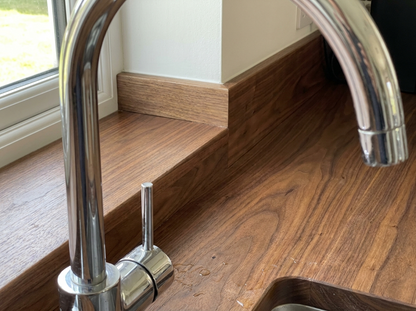 Solid walnut worktop and matching upstand behind a chrome tap
