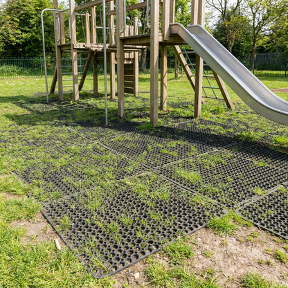 Rubber grass safety mats under a playground climbing frame and slide in a park