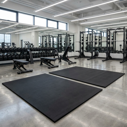 Large rubber gym mats side by side in a commercial gym free-weights area
